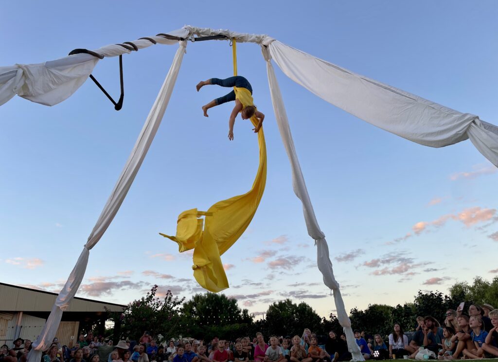 A performer spinning in the air using a piece of fabric